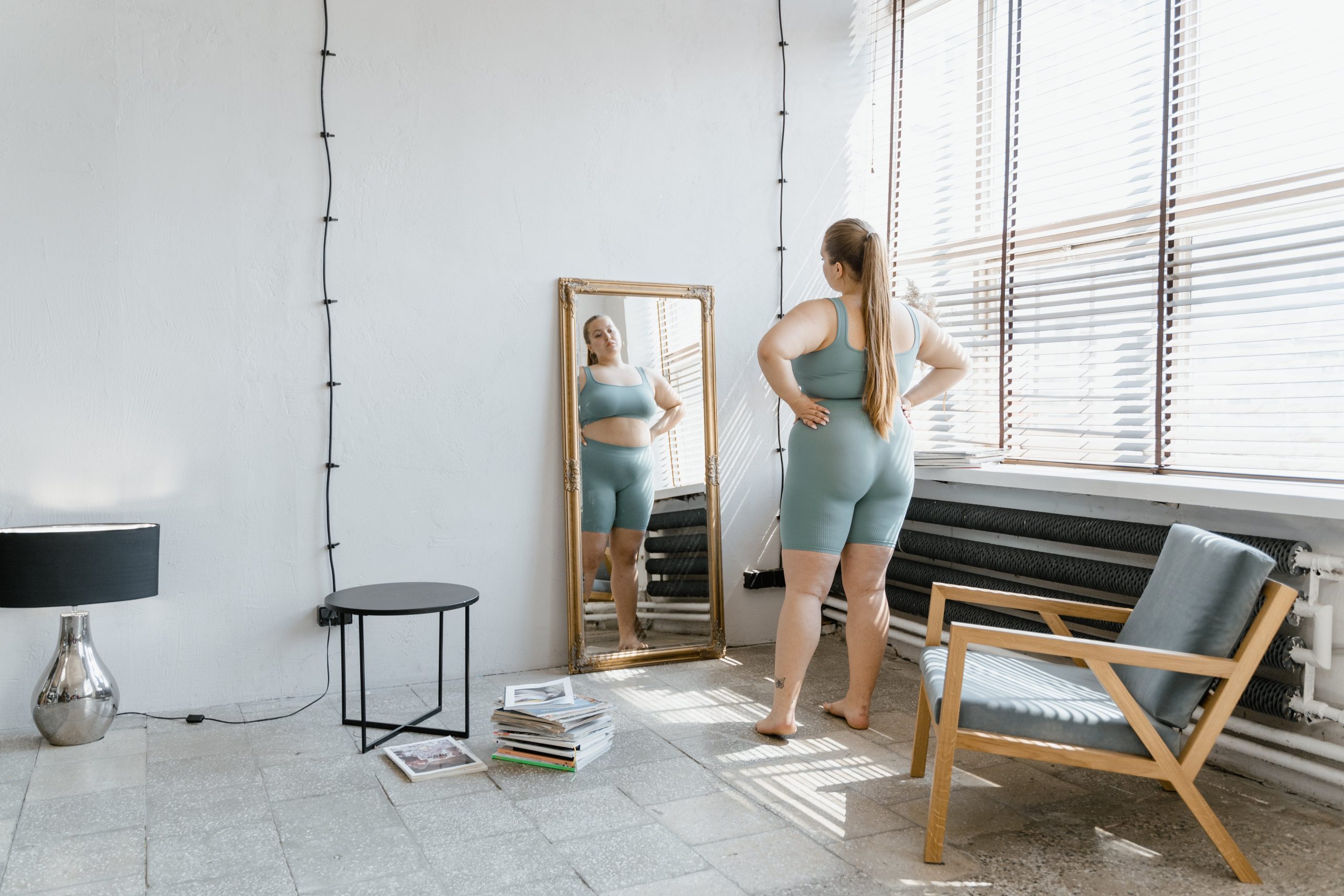 A photo of a woman looking in the mirror stressed and overweight