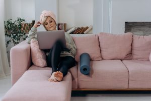 A-photo-of-a-woman-sitting-on-a-couch-with-her-legs-elevated-on-a-pillow